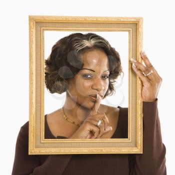 Royalty Free Photo of a Woman Holding a Frame around Her Head and a Finger Up to Her Lips