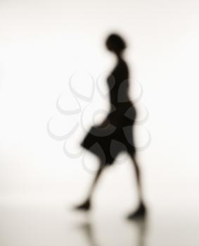 Soft focus silhouette of walking businesswoman holding briefcase.