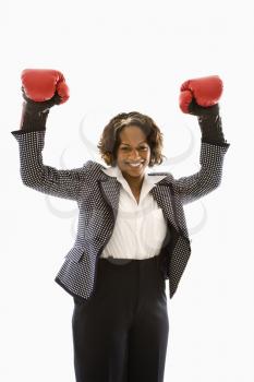 Royalty Free Photo of a Businesswoman Wearing Boxing Gloves Holding Arms Up in a Victory Stance and Smiling