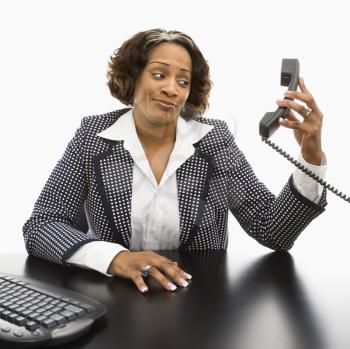 Royalty Free Photo of a Businesswoman Sitting at a Desk Holding Out a Telephone Receiver 