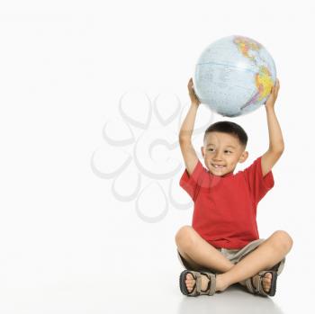 Royalty Free Photo of a Boy Sitting on the Floor Holding a Globe Over His Head