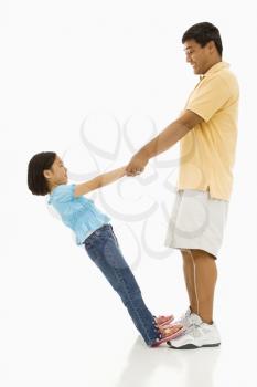 Royalty Free Photo of a Daughter Standing on Her Father's Feet Holding His Hands and Leaning Back