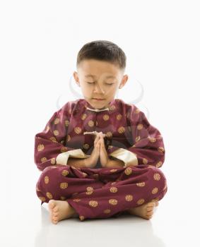 Royalty Free Photo of a Boy Sitting and Meditating in Traditional Attire