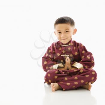 Royalty Free Photo of an Asian boy Sitting and Meditating in Traditional Attire