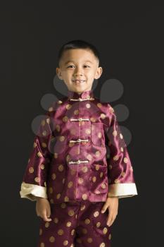 Royalty Free Photo of a Boy Standing Against a Black Background in Traditional  Attire