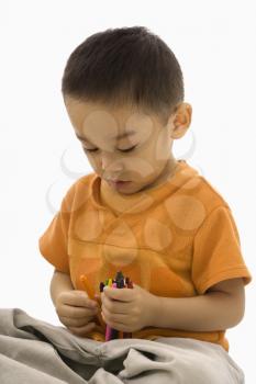 Royalty Free Photo of a Boy Sitting Holding a Handful of Crayons