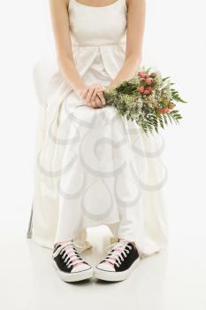 Royalty Free Photo of a Bride Holding a Bouquet Exposing Her Tennis Shoes