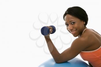Royalty Free Photo of an African American Woman Leaning on an Exercise Ball Holding a Dumbbell