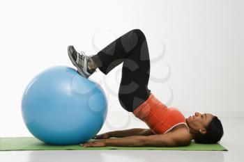 Royalty Free Photo of a Woman Stretching on a Mat With Her Feet on an Exercise Ball