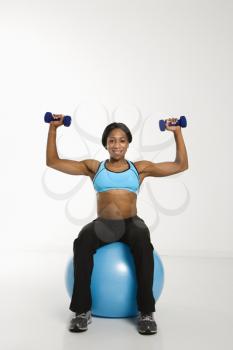 Royalty Free Photo of a Smiling Woman Sitting on an Exercise Ball Holding Dumbbells