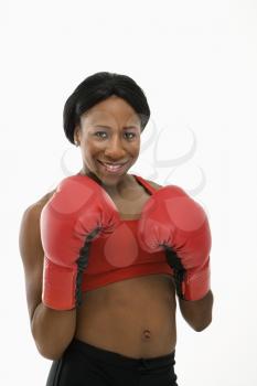 African American young adult woman wearing boxing goves smiling at viewer.