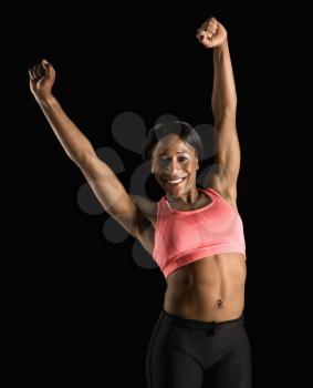 Royalty Free Photo of a Smiling African American Woman in a Sports Bra Stretching Arms Above Her Head