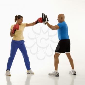 Royalty Free Photo of a Woman Standing and Punching Focus Mitts Worn by a Man