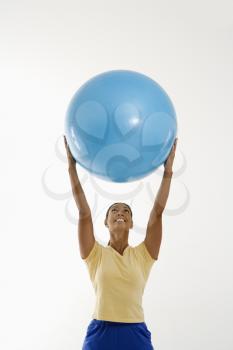 Royalty Free Photo of a Woman Standing and Holding an Exercise Ball Over Her Head