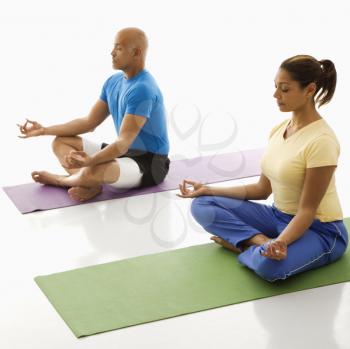 Royalty Free Photo of a Man and Woman Sitting in Lotus Position on Exercise Mats