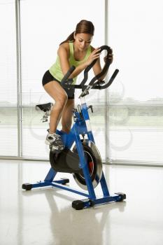 Royalty Free Photo of a Woman Pedaling an Exercise Bicycle Indoors