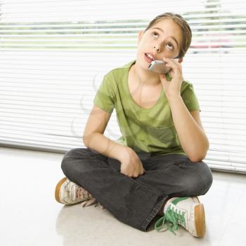 Royalty Free Photo of a Girl Sitting on the Floor Talking on a Cellphone