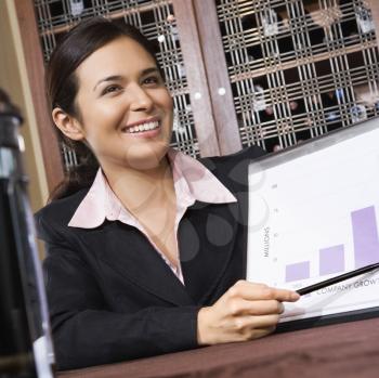 Royalty Free Photo of a Businesswoman Smiling and Pointing to a Bar Graph