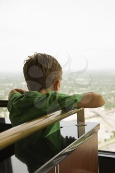 Young Caucasian boy leaning on railing at observation deck at Tower of the Americas in San Antonio, Texas.