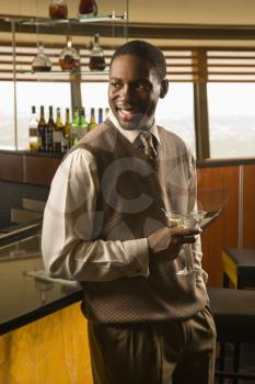 Royalty Free Photo of an African American Man Standing at a Bar With a Martini