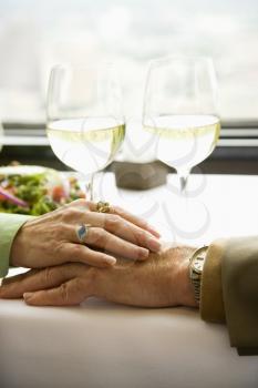 Royalty Free Photo of an Older Couple at a Restaurant Table With Woman's Hand Resting on Man's Hand