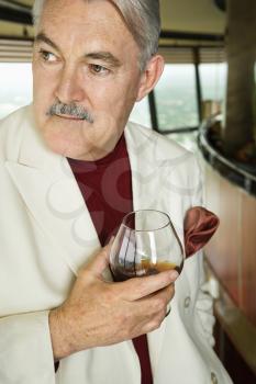 Royalty Free Photo of an Older Man in a Suit Holding a Snifter of Brandy
