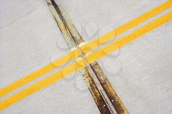 Royalty Free Photo of a Detail of a Solid Double Yellow Line in Road, Crossing Metal Strips in Cement