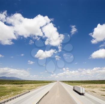 Royalty Free Photo of a Highway With a Tractor Trailer Truck and Blue Cloudy Sky
