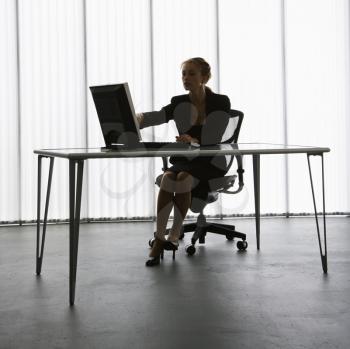 Silhouette of Caucasian businesswoman sitting at desk with computer working.