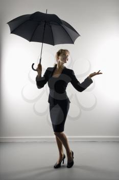 Businesswoman holding umbrella and gesturing.