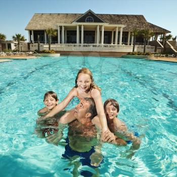 Royalty Free Photo of a Family at a Pool With a Clubhouse in the Background