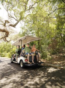 Caucasian family riding on golf cart on trail in North Carolina, USA.