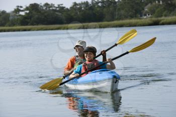Royalty Free Photo of a Couple Smiling and Paddling in a Kayak