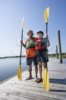 Royalty Free Photo of a Couple Standing on a Boat Dock Holding Paddles and Smiling