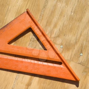 Royalty Free Photo of a Triangular Ruler on Unfinished Wood