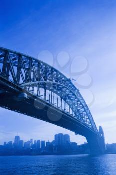 Low angle view of Sydney Harbour Bridge in Australia with view of harbour and downtown skyline.