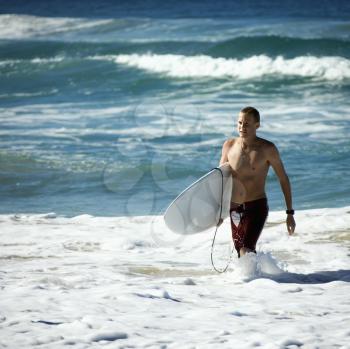 Royalty Free Photo of a Man Walking in the Ocean Carrying a Surfboard in Surfers Paradise, Australia