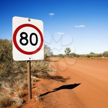 Australian kilometer per hour speed limit sign by rural dirt road.