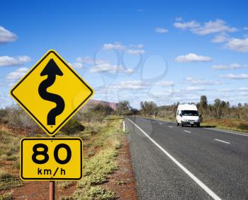 Royalty Free Photo of a Van on a Road in Rural Australia With Speed Limit and Curve Ahead Road Sign