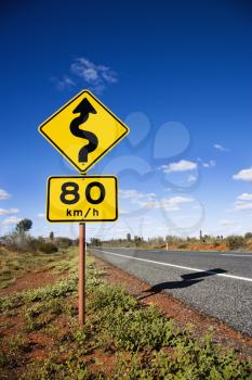 Royalty Free Photo of a Kilometer Per Hour Speed Limit and Curve Ahead Road Signs in Rural Australia