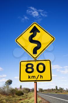 Royalty Free Photo of a Kilometer Per Hour Speed Limit and Curve Ahead Road Signs in Rural Australia