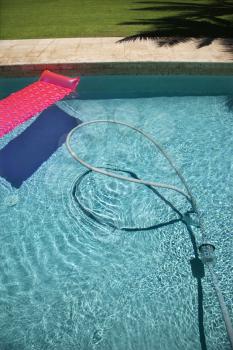 Royalty Free Photo of a Pink Float and Vacuum Hose in a Swimming Pool