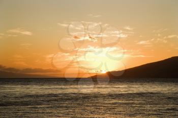 Royalty Free Photo of a Sun Setting Behind Island off Maui, Hawaii