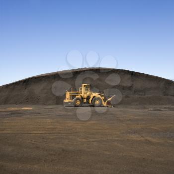 Royalty Free Photo of a Yellow Bulldozer Parked Beside a Large Mound of Dirt and Rock