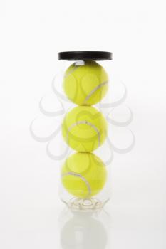 New tennis balls stacked in plastic container.