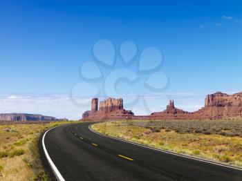 Royalty Free Photo of a Road in a Desert Landscape With Mesa and Mountains