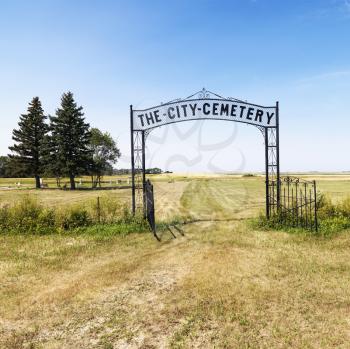Royalty Free Photo of an Entrance to a Rural Cemetery in a Field With a Decorative Iron Gate