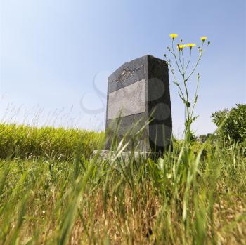 Royalty Free Photo of a Marble Headstone in a Rural Field Under a Blue Sky