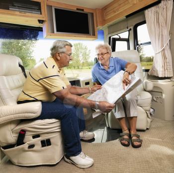 Royalty Free Photo of a Senior couple sitting in RV looking at map and smiling