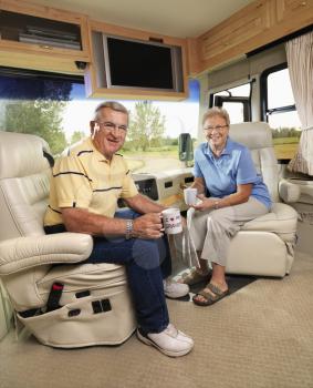 Royalty Free Photo of a Senior Couple Sitting in a RV Holding Coffee Cups and Smiling